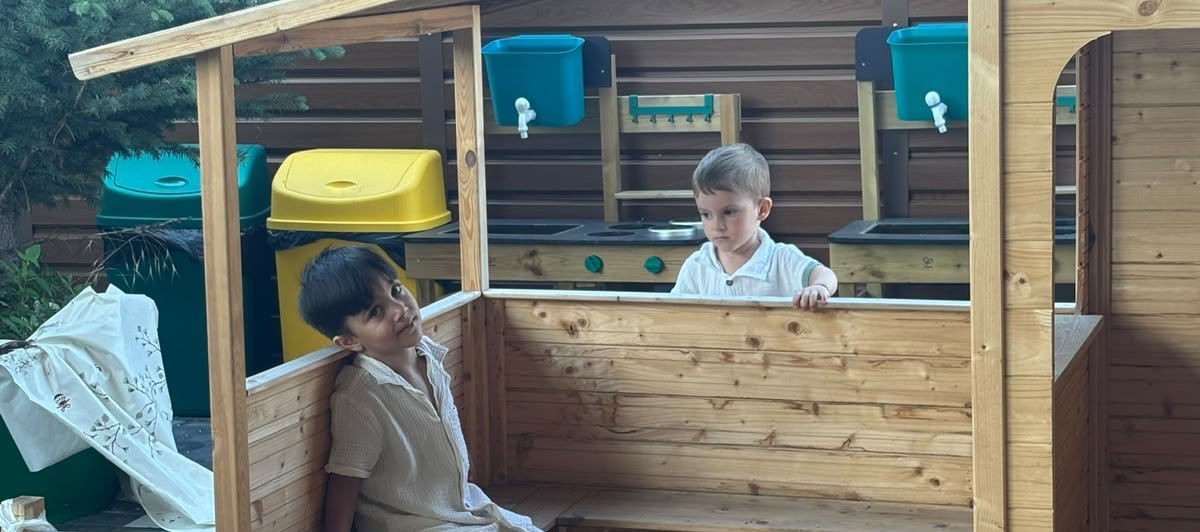 Copii jucându-se la bucătăriile de exterior din lemn